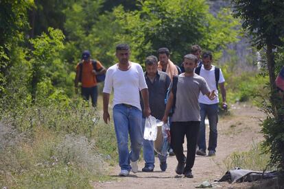 Migrantes caminan junto a la cerca de un refugio temporal en el lado serbio de la frontera con Hungría, el 5 de julio.