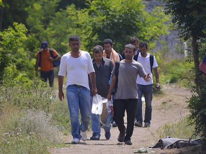 Migrantes caminan junto a la cerca de un refugio temporal en el lado serbio de la frontera con Hungr&iacute;a, el 5 de julio.  