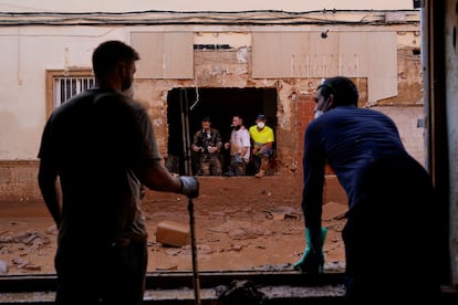 Vecinos observan una calle cubierta por barro tras la dana, el martes en Valencia.