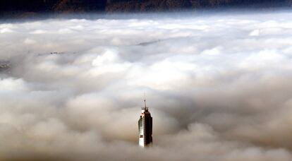 Vista de un edificio que se asoma por encima de la boina de contaminación que cubre los alrededores de la ciudad bosnia de Sarajevo, una de las que más posee más contaminación del aire en el mundo, con un índice de calidad del aire (ICA) de 164.