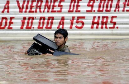 A young man carrying a computer wades through a flooded street in Acapulco.