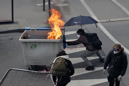 Un joven empuja un contenedor en llama en los disturbios tras las manifestaciones de este martes en Nantes.