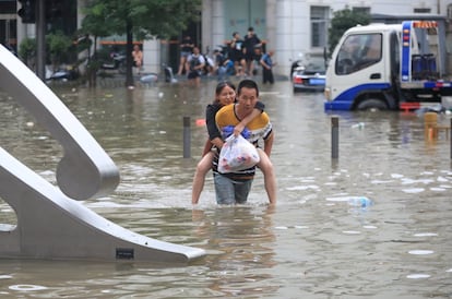 El temporal ha forzado también a movilizar al ejército, ante la amenaza de desplome de una presa cercana a Zhengzhou, de 10 millones de habitantes, capital de la provincia de Henan. En la imagen, dos personas cruzan una calle inundada de la ciudad.