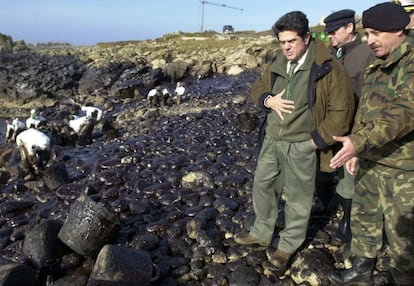 El ministro de Defensa, Federico Trillo, observa una cala de Lira donde el Regimiento Extremadura realiza las labores de descontaminación de fuel del vertido del Prestige, dentro de la visita del ministro a las tropas del Ejército español que colaboran en las tareas de limpieza en Galicia, el 23 de diciembre de 2002.