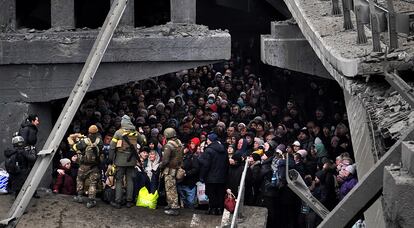 Ciudadanos ucranios intentan pasar por debajo de un puente destruido en Irpín, cerca de Kiev, el 5 de marzo