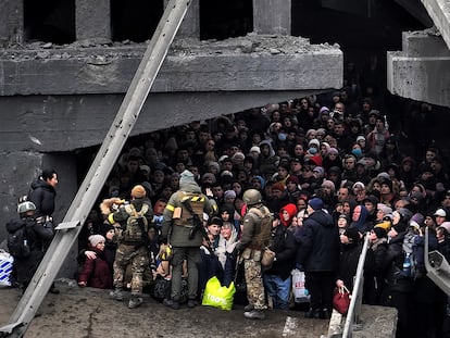 Ciudadanos ucranios intentan pasar por debajo de un puente destruido en Irpín, cerca de Kiev, el 5 de marzo