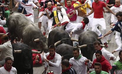 Un mozo es volteado por un toro de la ganadería Miura en el último encierro.