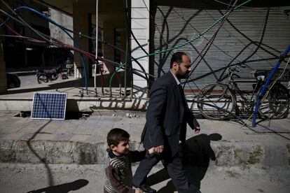 Habitantes del barrio de Douma (Damasco), bajo control de los rebeldes, pasan ante una red de tuberías de agua.