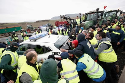 Varios agricultores mueven coches de la Guardia Civil para acceder a Pamplona este jueves.