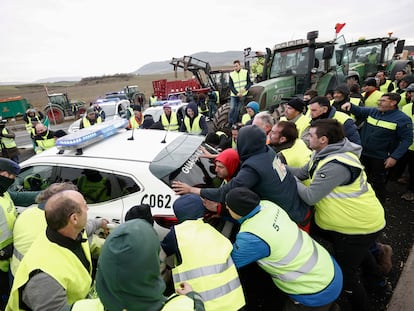 Varios agricultores mueven coches de la Guardia Civil para acceder a Pamplona este jueves.