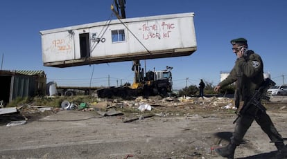 Un policía fronterizo israelí pasa junto a una casa prefabricada, mientras es retirada, este martes durante la demolición del asentamiento ilegal judío de Amoná, en Cisjordania.