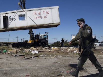 Un policía fronterizo israelí pasa junto a una casa prefabricada, mientras es retirada, este martes durante la demolición del asentamiento ilegal judío de Amoná, en Cisjordania.