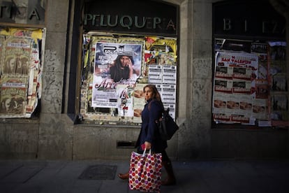 Una mujer camina junto a un establecimiento cerrado en la calle del Pez, en pleno barrio de Malasaña. En los últimos cinco años se calcula que han cerrado cerca de 9.700 establecimientos comerciales solo en la capital, a un ritmo de 160 al mes. Daban trabajo a unas 25.000 personas.