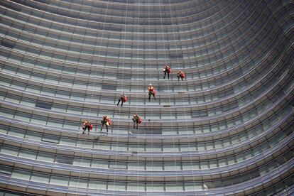 Operarios limpian las ventanas a lo largo de la torre de Unicredit en Milán (Italia).