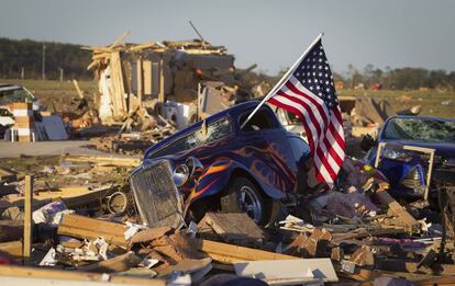 Um carro com a bandeira dos Estados Unidos entre os escombros de uma casa em um bairro próximo a Vilonia, Arkansas.