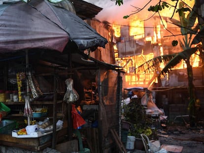 Una vendedora recoge sus bienes de un puesto próximo a una casa en llamas tras un incendio en el suburbio de Quezon (Manila). 