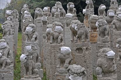 Varias estatuas de piedra, con forma de len, llevan mscaras de respiracin colocadas por los estudiantes de una academia de bellas artes, en Xi'an (China).