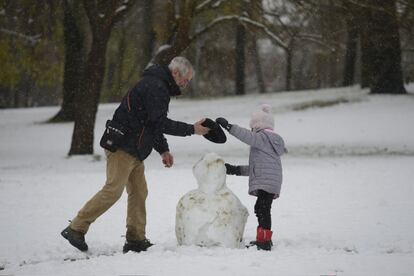 Abuelo le presta la boina a su nieta para el muñeco de nieve en Vitoria (Álava).