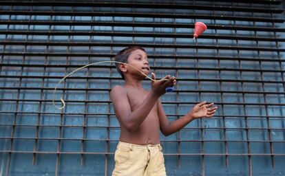 Un niño indio juega con una peonza en una calle de Bombay.