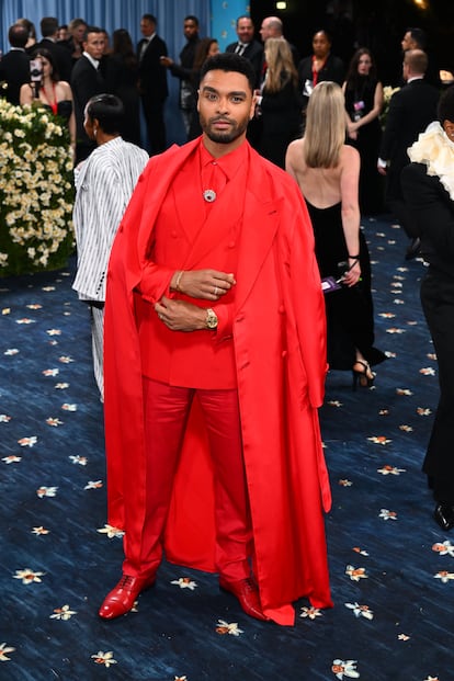 También con capa, pero totalmente de rojo de los pies a la cabeza, Rege-Jean Page. Conjunto de Brioni con joyas de Tiffany & Co.