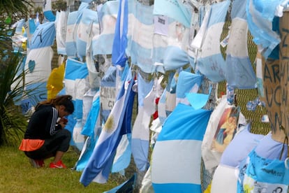 Mulher se ajoelha ante as bandeiras que homenageiam os 44 tripulantes do Ara San Juan, na base naval de Mar da Prata.