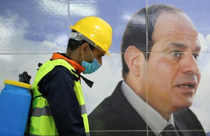 Un trabajador de un equipo médico desinfecta el metro de El Cairo, junto a una foto del mariscal Abdelfatá al Sisi, el pasado 22 de marzo.