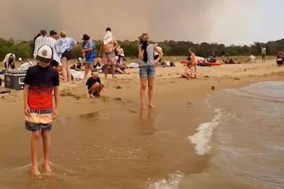 Un grupo de gente se refugia este martes de los incendios en Batemas Bay (Australia).