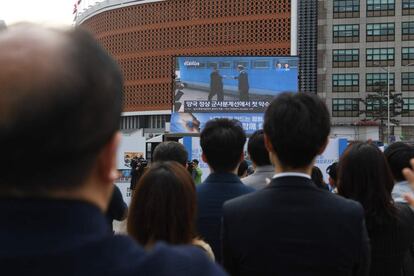 La gente mira el momento en el que ambos líderes se saludan en una pantalla de televisión en Seúl.