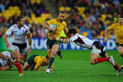 El australiano Quade Cooper intenta evitar ser placado por los estadounidenses.