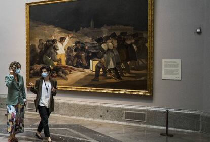 Dos visitantes del Prado pasan delante de 'Los fusilamientos' de Goya.