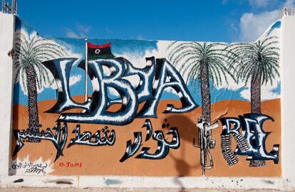 La bandera de los rebeldes libios, unas palmeras y un fusil acompañan el nombre del país en este mural de Tripoli.