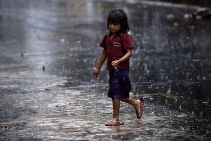 Una niña de la etnia Mbyá Guaraní camina para refugiarse de lluvia. Ella y su familia viven desde hace semanas enfrente del Instituto Paraguayo del Indígena pidiendo tierras para poder vivir. En la mano lleva un vaso para poder beber en el lugar donde se protejan mientras esperan a que deje de llover.