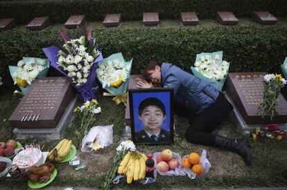 La madre del bombero Zhang Qian llora sobre la tumba de su hijo en un cementerio para mártires, al cumplirse 100 días de la cadena de explosiones el puerto de Tianjin.