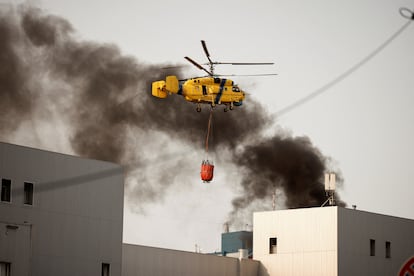 Un helicóptero de bomberos sobrevuela una columna de humo que se eleva cerca del lugar donde impactó un dron ruso en Kiev. 
