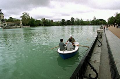 Tres jóvenes pasean en barca por el estanque del Retiro (arriba).