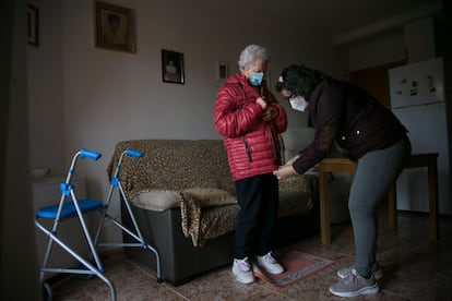 Una cuidadora atiende a una mujer mayor en su casa en Manzanares El Real (Madrid).