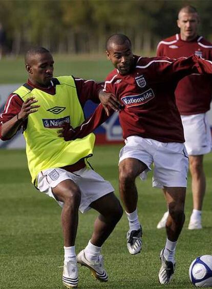 Ashley Cole protege el balón ante la entrada de Jermaine Defoe durante un entrenamiento de la selección inglesa.