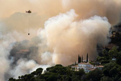 Un helicóptero de los bomberos de la Generalitat lanzaba agua este viernes sobre las llamas en Santa Cristina d'Aro (Girona)