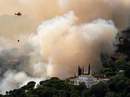 Un helicóptero de los bomberos de la Generalitat lanzaba agua este viernes sobre las llamas en Santa Cristina d'Aro (Girona)