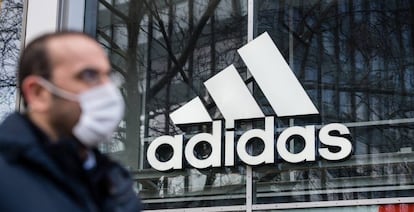 Logotipo de Adidas reflejado en una de sus tiendas. Adidas gana 31 millones de euros hasta marzo, un 95,1 % menos que un año antes. 