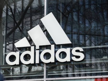 Logotipo de Adidas reflejado en una de sus tiendas. Adidas gana 31 millones de euros hasta marzo, un 95,1 % menos que un año antes.