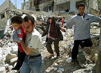 Una familia palestina corre sobre los escombros de su casa en Yenn.