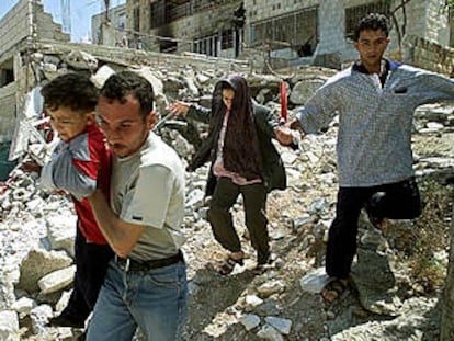 Una familia palestina corre sobre los escombros de su casa en Yenín.