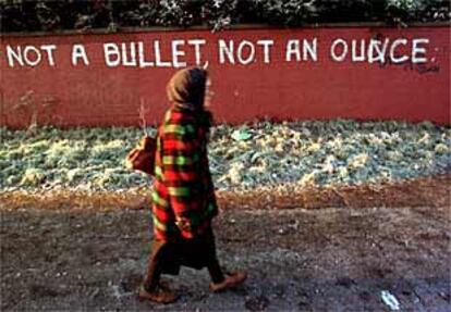 Una mujer camina junto a una pintada contra el desarme del IRA en Belfast. El mensaje dice: "Ni una bala ni una onza [de armas]".