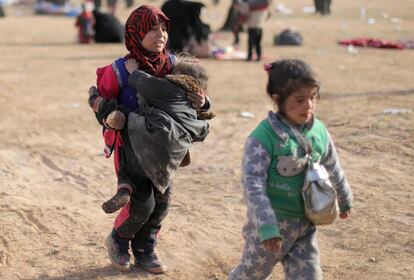 Una niña camina mientras carga con otra pequeña en brazos, en Baghouz, el último asentamiento del ISIS, asediado por las fuerzas kurdas, en la provincia siria norteña de Deir Ezzor.