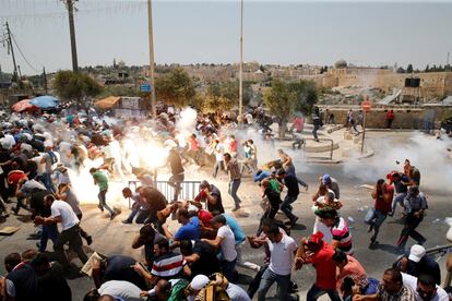 Manifestantes palestinos corren tras ser disparados gas lacrimógeno, en la Ciudad Vieja de Jerusalén.