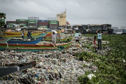 Un hombre recolecta materiales reciclables entre la basura en la bahía de Manila (Filipinas).
