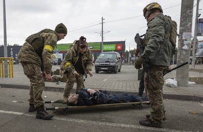 Militares ucranios ayudan a un herido en Irpin, cerca de Kiev.