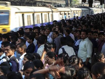 Centenares de viajeros esperan la llegada del tren en una estaci&oacute;n de Bombai (India).