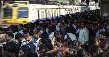Centenares de viajeros esperan la llegada del tren en una estaci&oacute;n de Bombai (India).